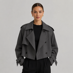 Modelo con gabardina corta cruzada en gris oscuro, vista frontal