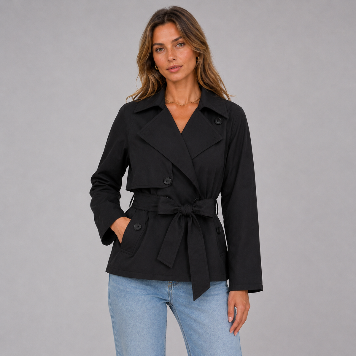 Modelo con gabardina corta en negro con cinturón anudado, vista frontal