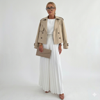 Modelo con chaqueta corta cruzada beige y falda plisada blanca