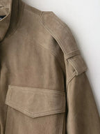 Detalle del cuello, la hombrera y el bolsillo con solapa de la chaqueta en tono topo